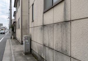 幹線道路沿いの家の外壁に、排気ガスや砂埃が付着し、黒ずんだ汚れとなっている様子